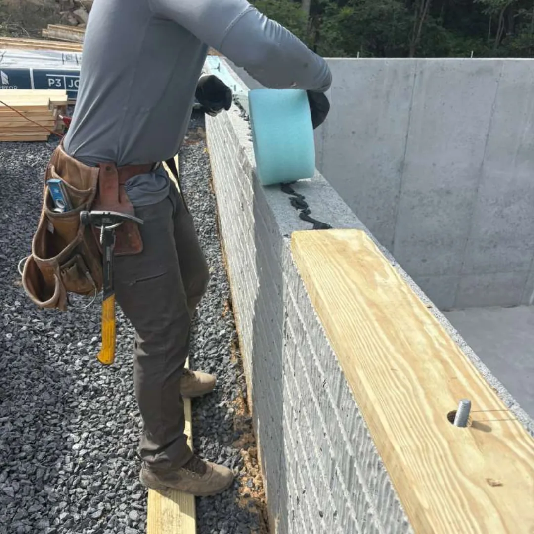 Worker installing foam insulation on a foundation wall.