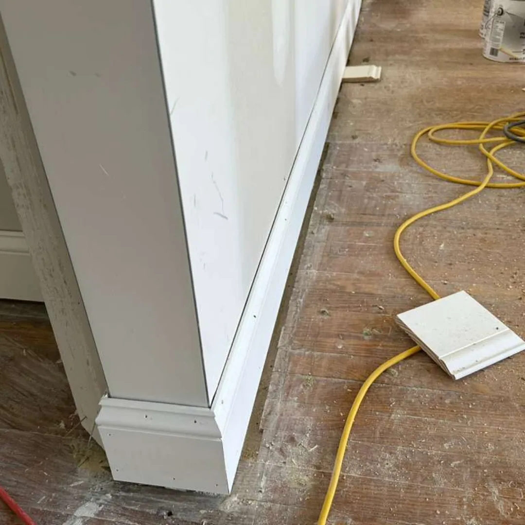 Trim work on a white wall and baseboard.