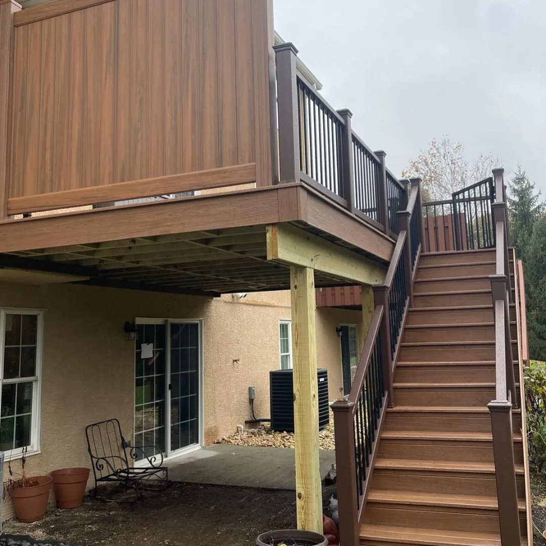 Two-story brown deck with privacy wall and stairs.