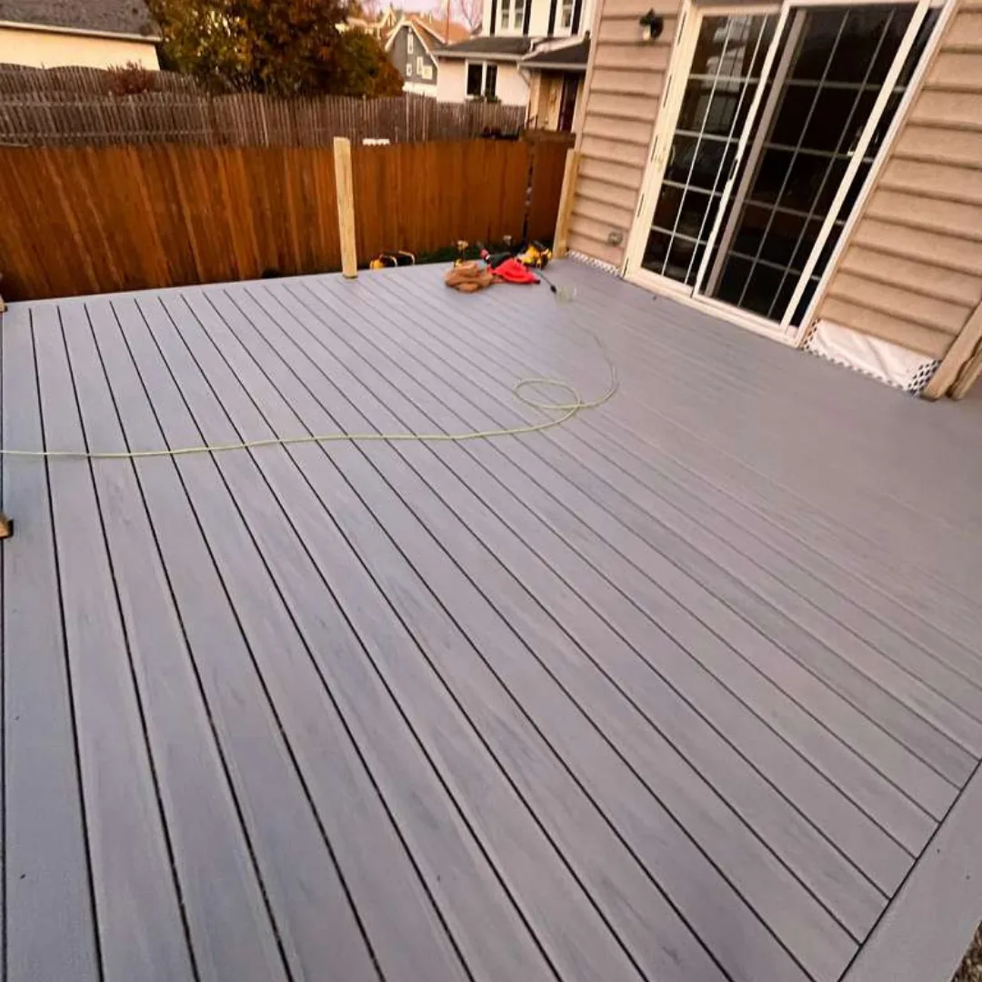 Newly installed gray composite deck with brown fence.
