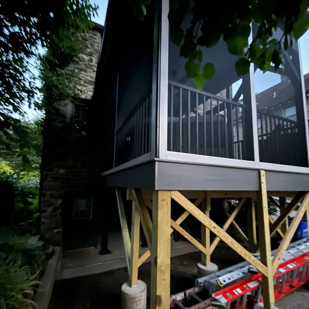 Screened porch with wood frame and stone house.