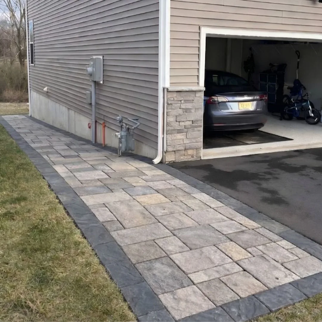 New paver walkway alongside a house and garage.
